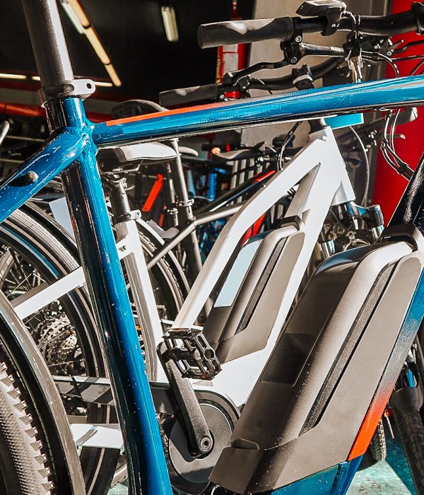 Das Bild zeigt mehrere E-Bikes hintereinander. Das vorderste E-Bike hat einen blauen Rahmen und ist wohl ein Mountainbike.