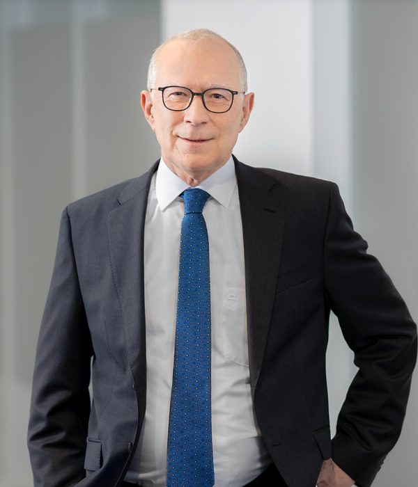 Vorstandsmitglied Volker Stern steht mit offenen dunkelgrauen Sakko neben einer Wand. Er trägt eine blaue Krawatte. Seine linke Hand hat er auf seiner linken Hüfte abgestützt, seine rechte Hand hängt an der Seite herunter.