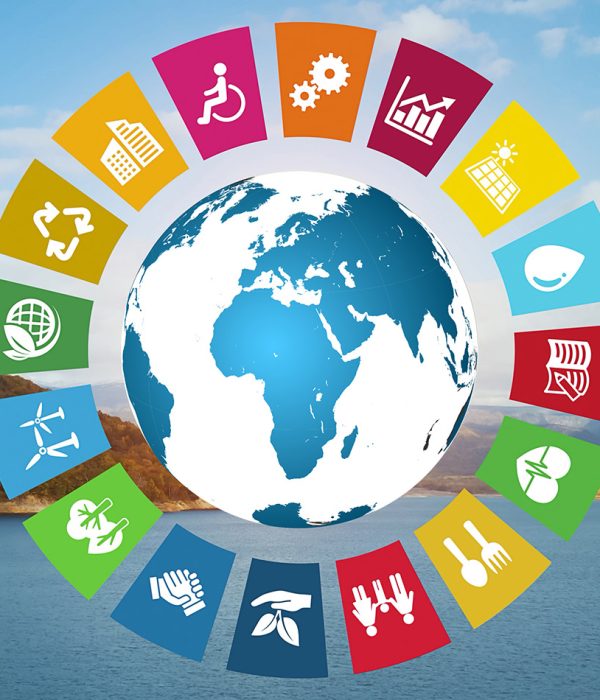 Das Bild zeigt eine Weltkugel, auf der v.a. Europa und Afrika zu sehen sind. Die gezeigten Länder sind blau, die Meere weiß. Um die Weltkugel herum sind Icons der 16 UN-Nachhaltigkeitsziele zu sehen, etwa ein Regentropfen, eine Familie, ein Rollstuhlfahrer oder ein Herz. Der Hintergrund des Bildes besteht aus einem Landschaftsbild, auf dem ein See und dahinter Wald und Hügel zu sehen sind.